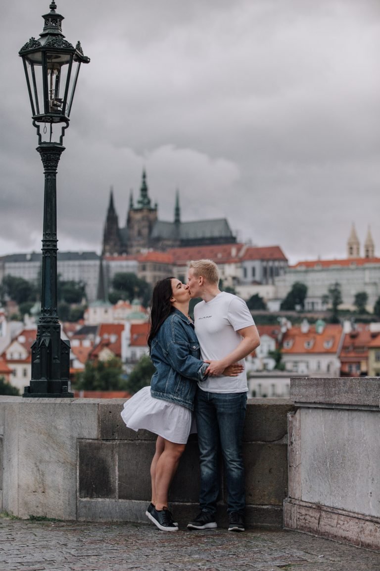 Couple embracing during a photoshoot with a city skyline behind them