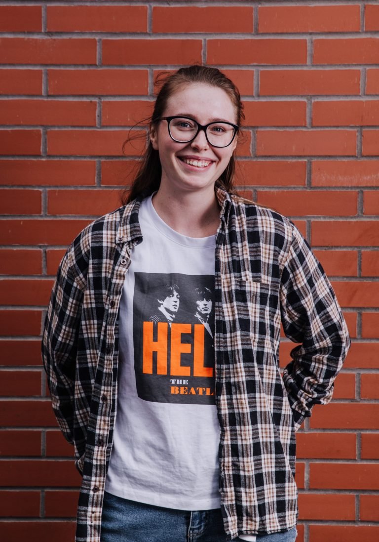 Relaxed portrait of a smiling young woman against a brick wall