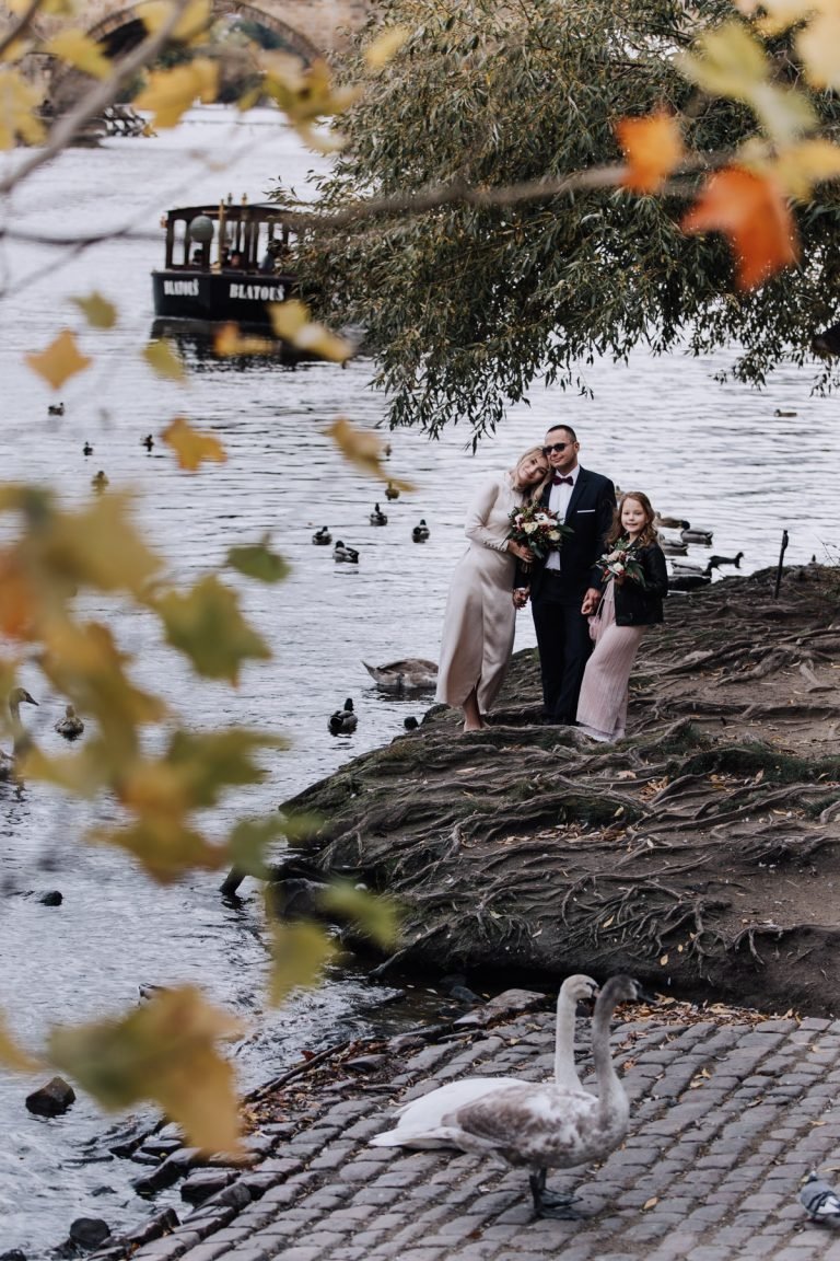 Couple and child photographed by a river in autumn after an intimate wedding